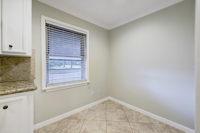 unfurnished dining area with baseboards, ornamental molding, and light tile patterned floors