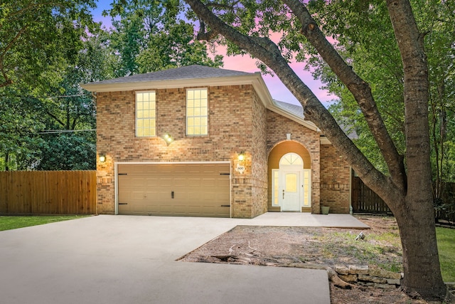 traditional home with concrete driveway, brick siding, fence, and a garage