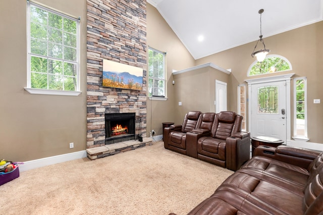 carpeted living room with crown molding, high vaulted ceiling, a stone fireplace, and baseboards