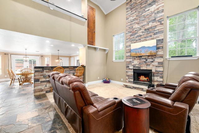 living area featuring crown molding, baseboards, a fireplace, and a wealth of natural light