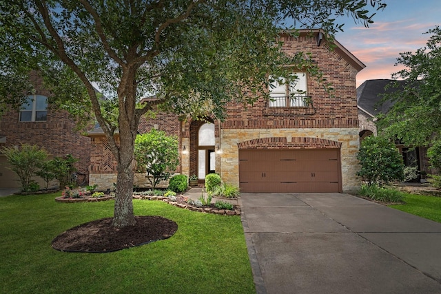 traditional-style house with a yard, an attached garage, concrete driveway, and a balcony