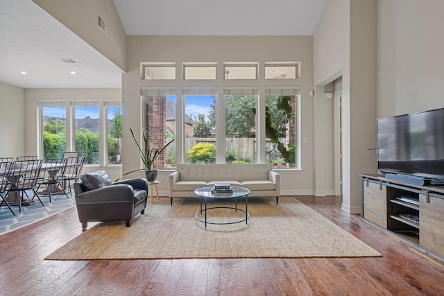 living area featuring wood-type flooring, a towering ceiling, and visible vents