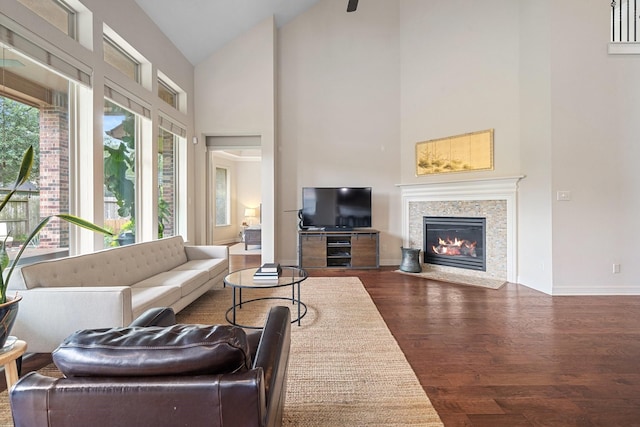 living room with a fireplace with flush hearth, high vaulted ceiling, baseboards, and wood finished floors