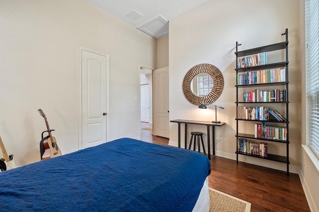 bedroom with baseboards, attic access, and wood finished floors