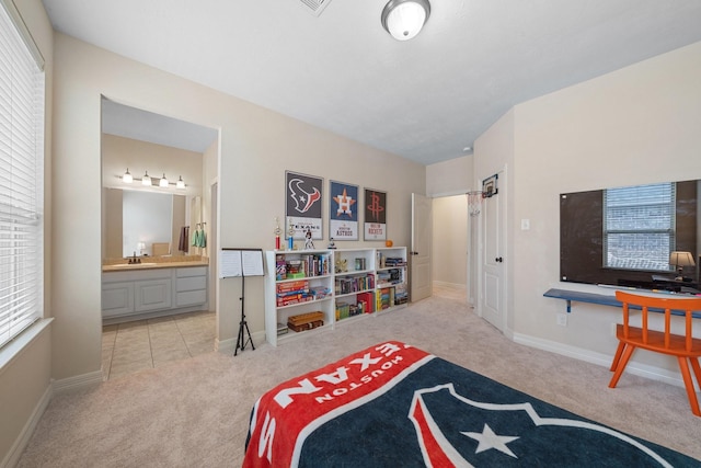 carpeted bedroom featuring connected bathroom, baseboards, and a sink