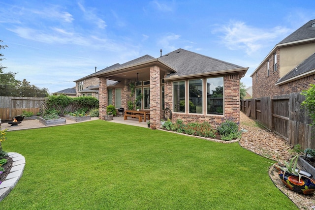 back of house featuring brick siding, a yard, a vegetable garden, and a patio