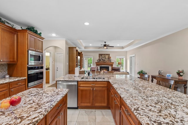 19486 Humaya Dr, Porter, TX 77365 - kitchen with a sink, a lit fireplace, light stone counters, a ceiling fan, and appliances with stainless steel finishes