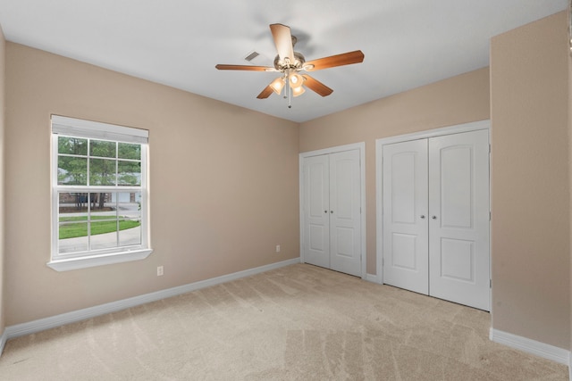19486 Humaya Dr, Porter, TX 77365 - unfurnished bedroom featuring baseboards, a ceiling fan, two closets, and light carpet