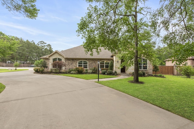 19486 Humaya Dr, Porter, TX 77365 - view of front facade featuring roof with shingles, curved driveway, fence, a front lawn, and stone siding