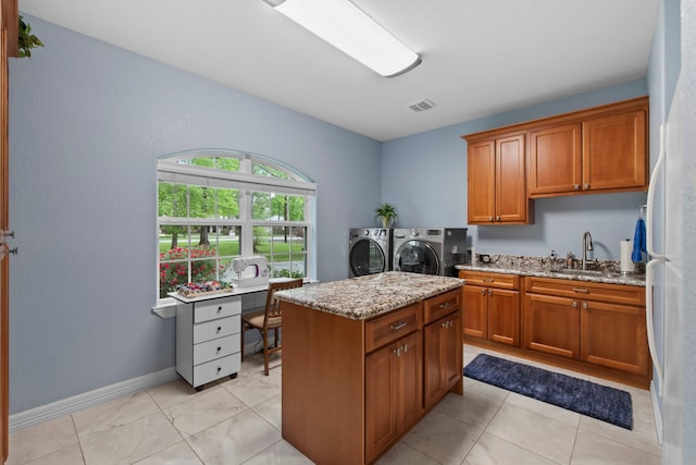 19486 Humaya Dr, Porter, TX 77365 - kitchen featuring a center island, brown cabinets, a sink, light stone counters, and washer and dryer