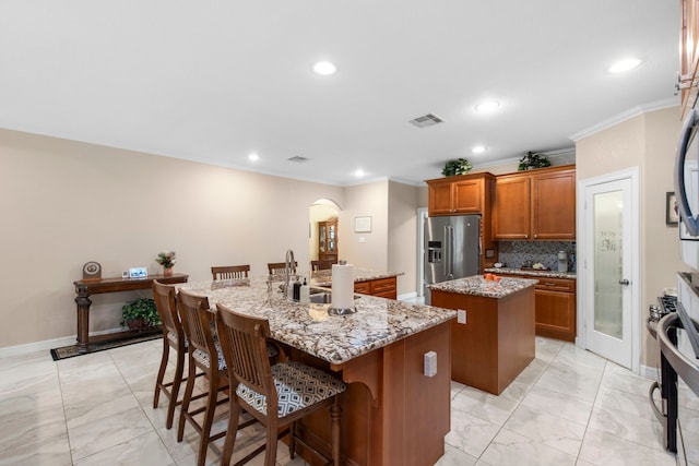 19486 Humaya Dr, Porter, TX 77365 - kitchen featuring brown cabinets, a sink, a kitchen island with sink, visible vents, and high quality fridge