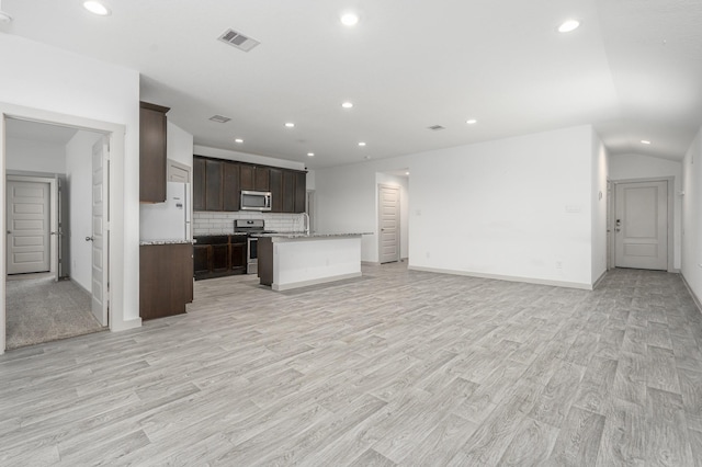 kitchen with recessed lighting, open floor plan, appliances with stainless steel finishes, and dark brown cabinetry