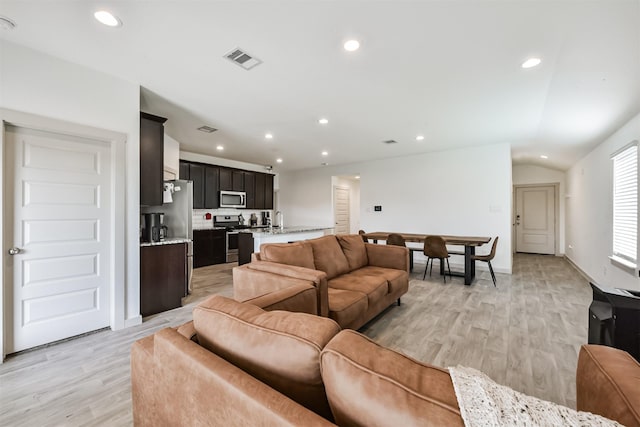 living room with visible vents, recessed lighting, vaulted ceiling, and light wood-type flooring