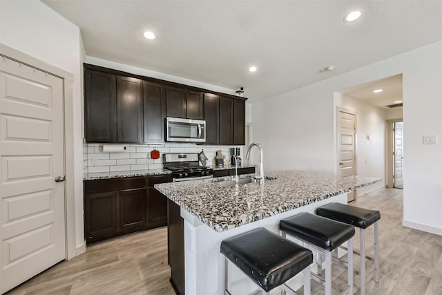 kitchen featuring a sink, appliances with stainless steel finishes, light stone countertops, and tasteful backsplash