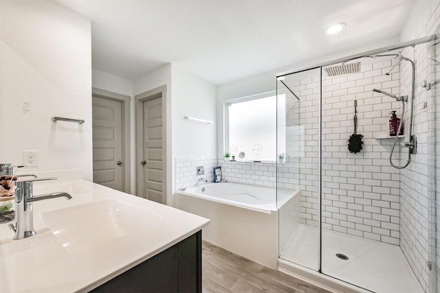 bathroom featuring wood finished floors, a bath, a sink, and a stall shower