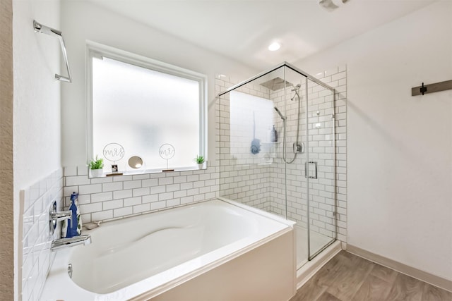 bathroom featuring wood finished floors, a garden tub, and a stall shower