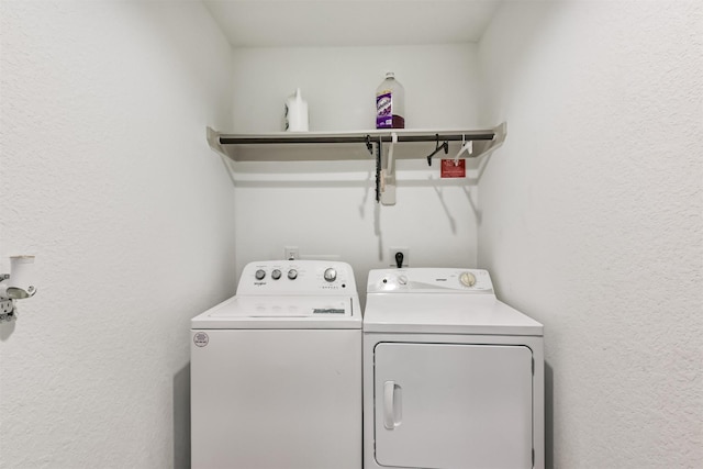washroom with a textured wall, laundry area, and washer and clothes dryer