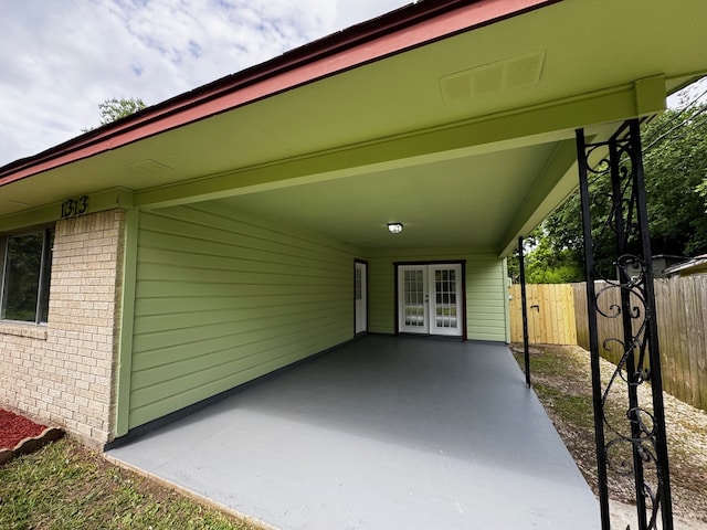 view of patio / terrace featuring french doors, fence, an attached carport, and visible vents