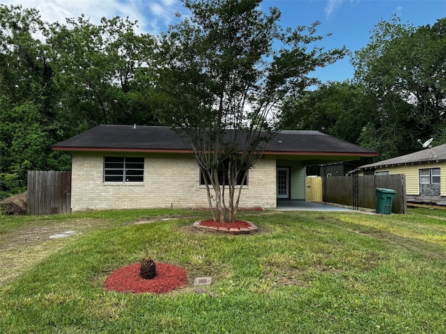 back of property featuring a lawn, an attached carport, fence, and brick siding