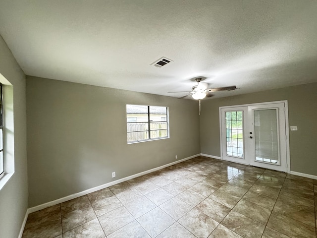 tiled spare room featuring visible vents, baseboards, ceiling fan, and a healthy amount of sunlight