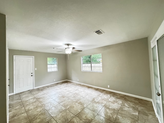 empty room with baseboards, a ceiling fan, a textured ceiling, and visible vents