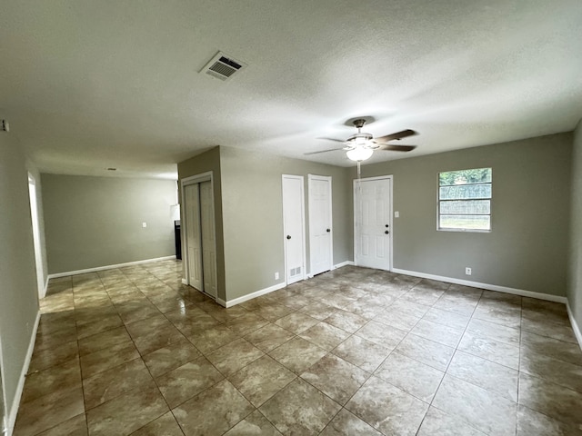 tiled spare room with a ceiling fan, baseboards, visible vents, and a textured ceiling