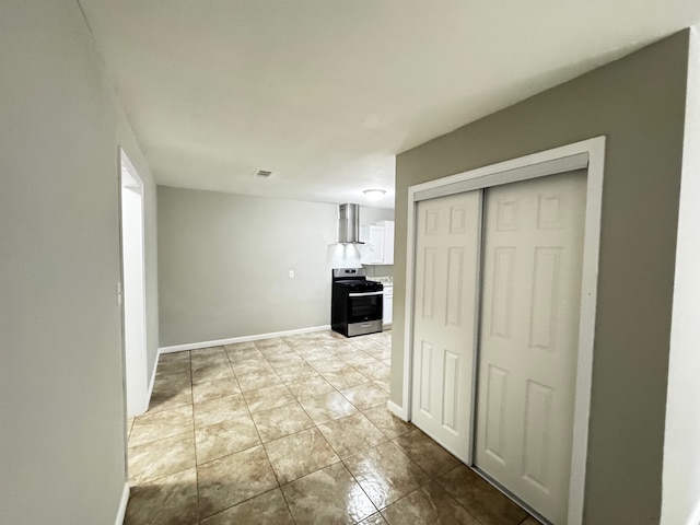 kitchen featuring visible vents, gas range, light tile patterned floors, white cabinets, and wall chimney exhaust hood
