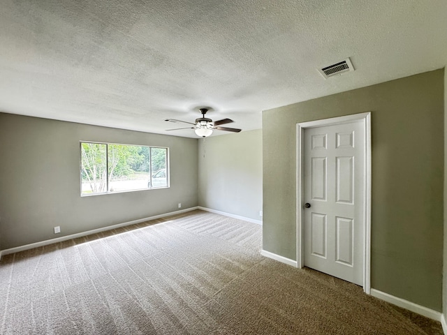 carpeted spare room with visible vents, a ceiling fan, baseboards, and a textured ceiling