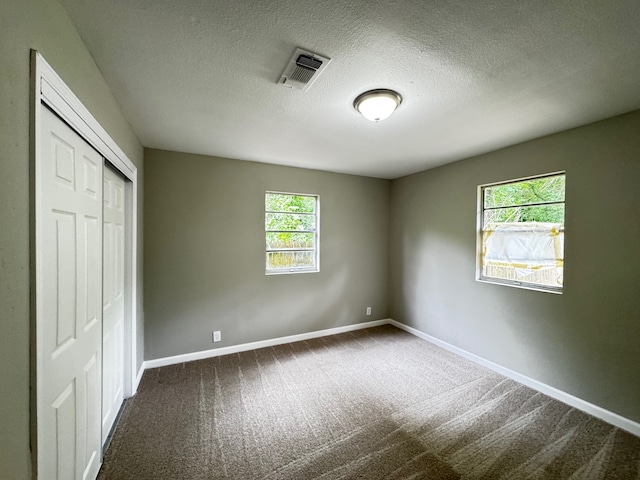 unfurnished bedroom with carpet floors, baseboards, a closet, and visible vents