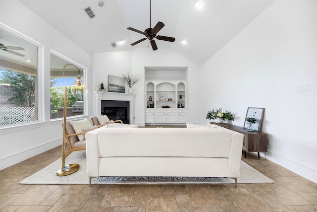 13614 Boerne Canyon Ln, Cypress, TX 77429 - living area featuring a ceiling fan, built in features, a glass covered fireplace, vaulted ceiling, and baseboards