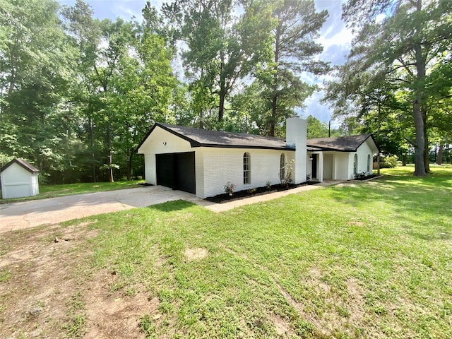 view of side of property with driveway, a yard, a chimney, brick siding, and a storage shed