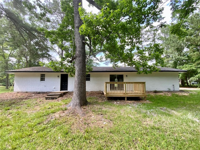 rear view of house featuring a wooden deck, a yard, and brick siding