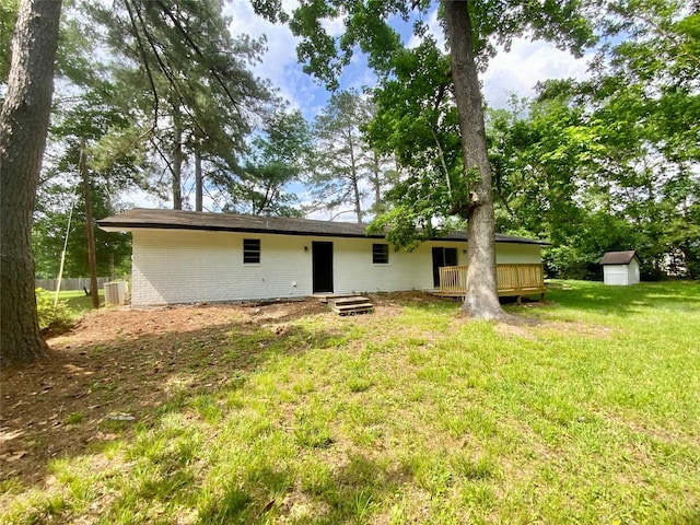 back of house with an outdoor structure, a deck, a storage unit, brick siding, and a lawn