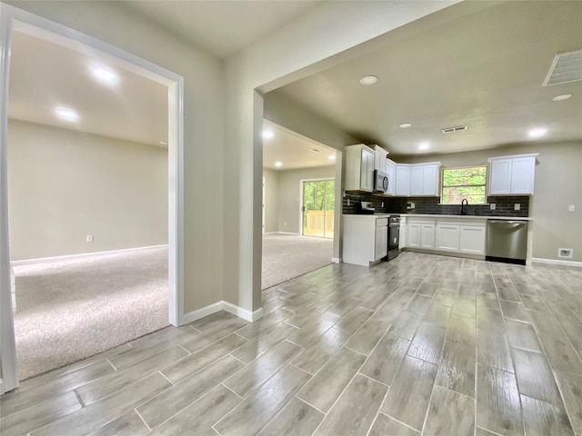 kitchen featuring baseboards, stainless steel appliances, wood finish floors, and a wealth of natural light
