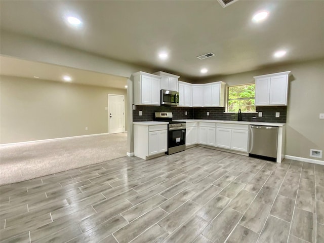 kitchen featuring visible vents, open floor plan, tasteful backsplash, light wood finished floors, and stainless steel appliances