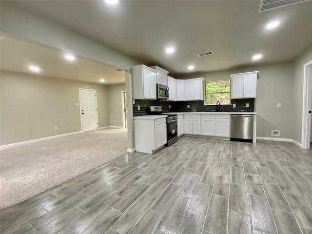 kitchen with visible vents, appliances with stainless steel finishes, a sink, baseboards, and open floor plan
