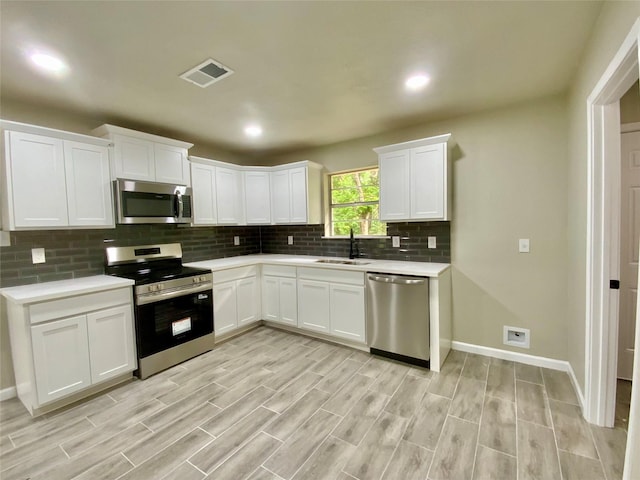 kitchen with visible vents, light countertops, tasteful backsplash, a sink, and appliances with stainless steel finishes