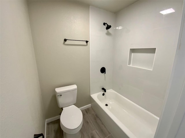 bathroom featuring baseboards, shower / bathtub combination, toilet, and wood finished floors