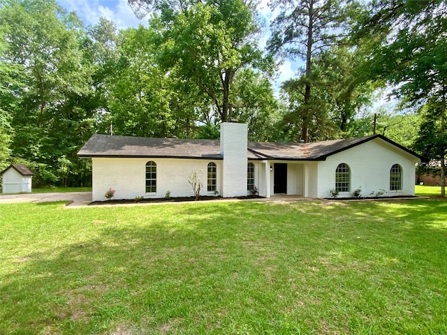 single story home with brick siding, a front yard, and a chimney