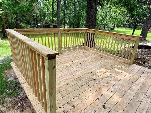 wooden terrace featuring a lawn and an outbuilding