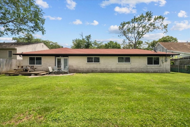 back of house featuring brick siding, fence, a yard, and a patio