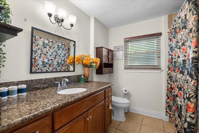 bathroom featuring tile patterned flooring, vanity, toilet, baseboards, and a textured ceiling