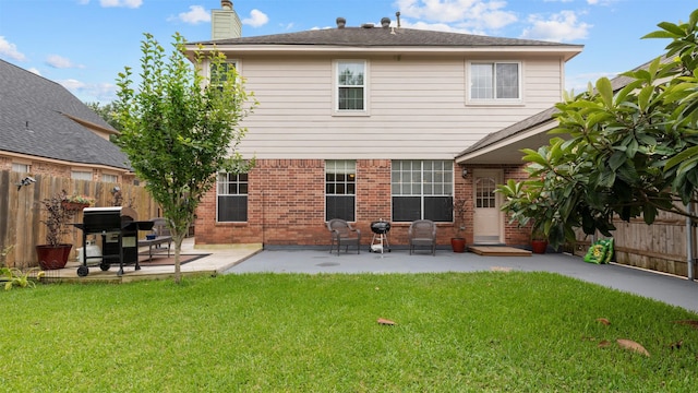 rear view of house featuring brick siding, a chimney, and a patio