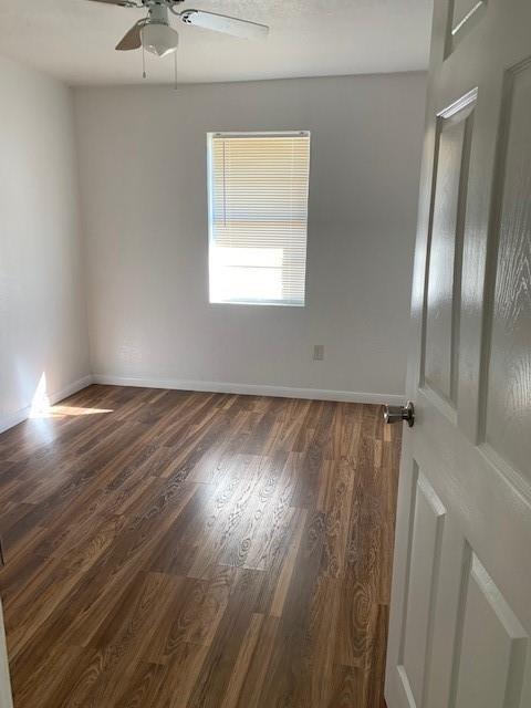 spare room featuring baseboards, a ceiling fan, and wood finished floors