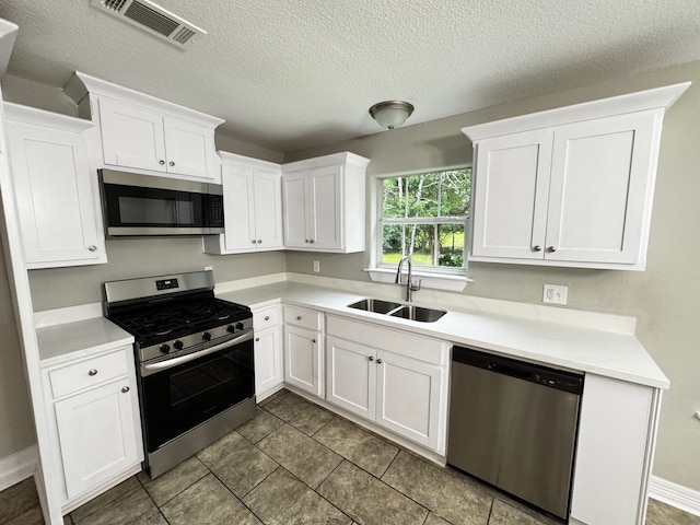 kitchen featuring light countertops, stainless steel appliances, white cabinetry, and a sink