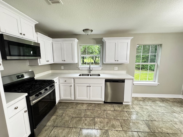 kitchen with a sink, light countertops, stainless steel appliances, and white cabinetry