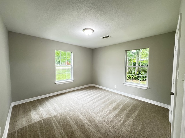 empty room with visible vents, carpet flooring, baseboards, and a textured ceiling