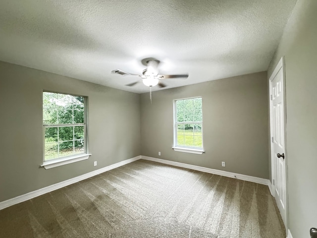 empty room featuring visible vents, a ceiling fan, baseboards, and a textured ceiling