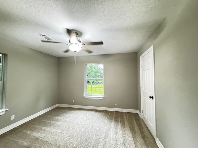 unfurnished room featuring visible vents, carpet floors, baseboards, ceiling fan, and a textured ceiling