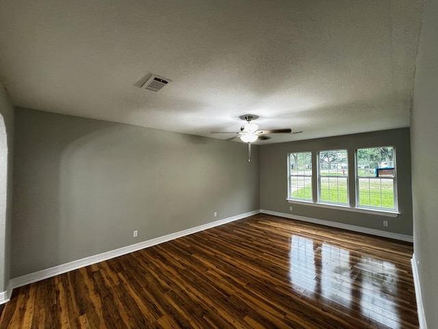 spare room with baseboards, ceiling fan, dark wood-style flooring, and visible vents